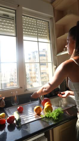 mujer lavando frutas y verduras en la cocina