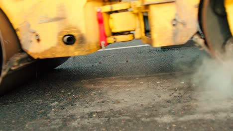 compactor is driving over freshly poured asphalt and compresses it on the road to fix a hole