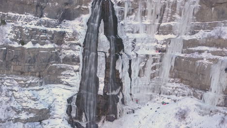 ice climbers climb a frozen waterfall in extreme conditions - zooming in