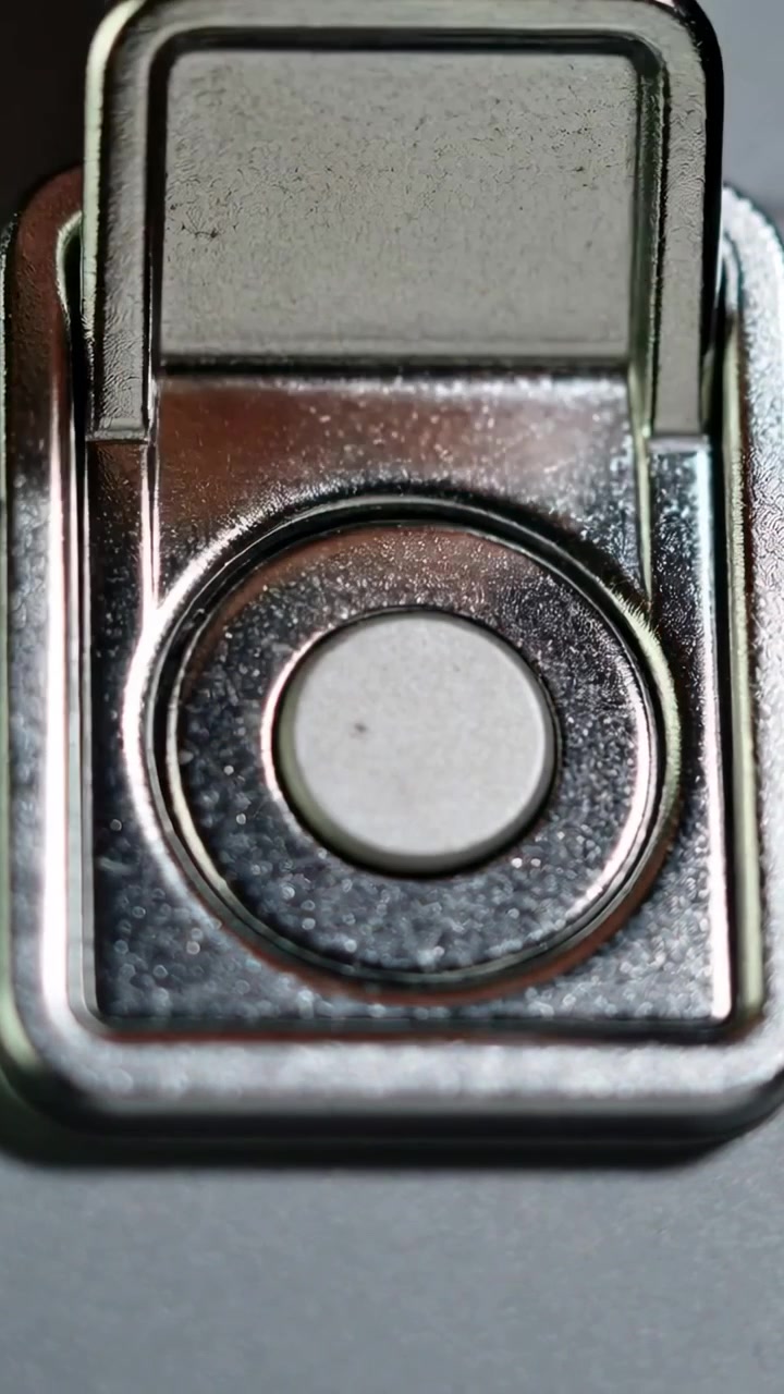 Vídeo vertical: Ponta do dedo pressionando o botão central em uma tranca de metal em close-up, travando a fechadura.