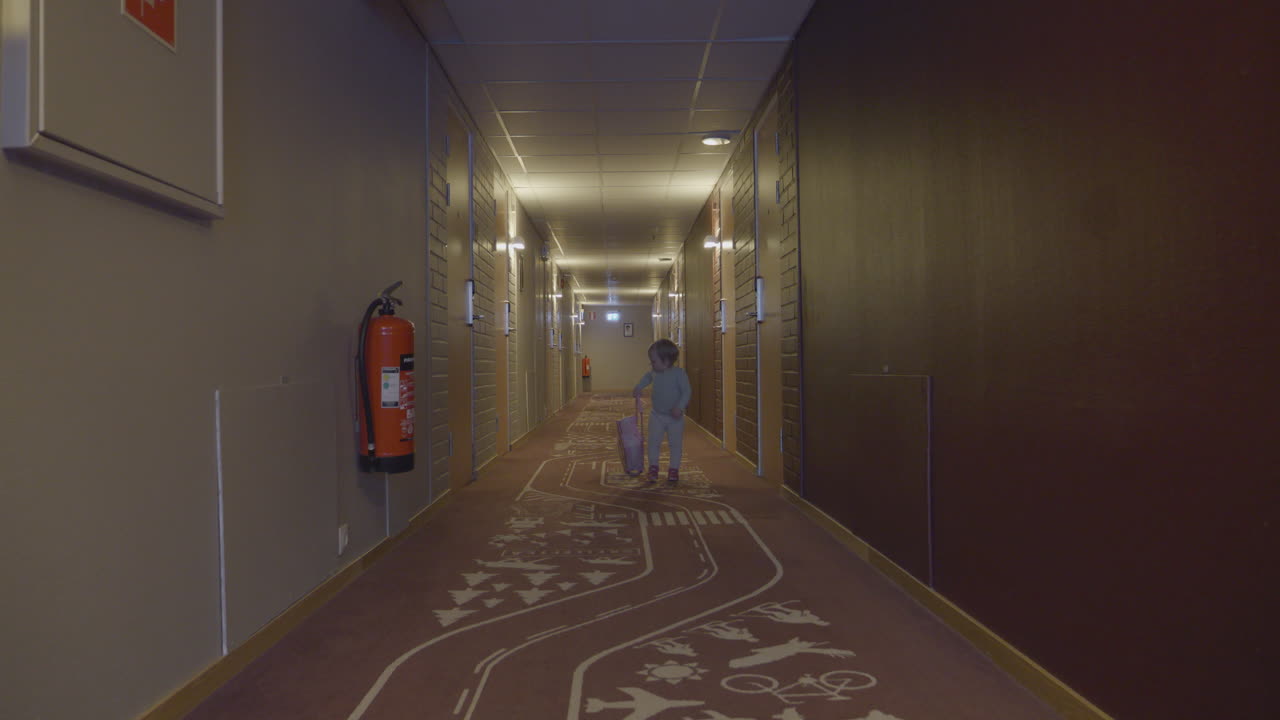 joven niño viajando caminando por el pasillo del hotel solo