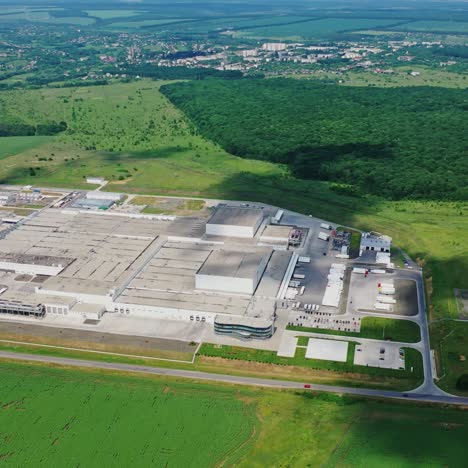 modern factory surrounded by nature. large area of industrial complex among green fields. manufacturing in natural environment. aerial view.