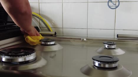 closeup woman uses yellow wipe to clean fire pit surface at home kitchen firmly