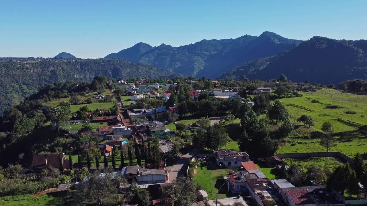 Drone flyby shot capturing forest, hills and ravines with a small village in the Mexican Sierra.