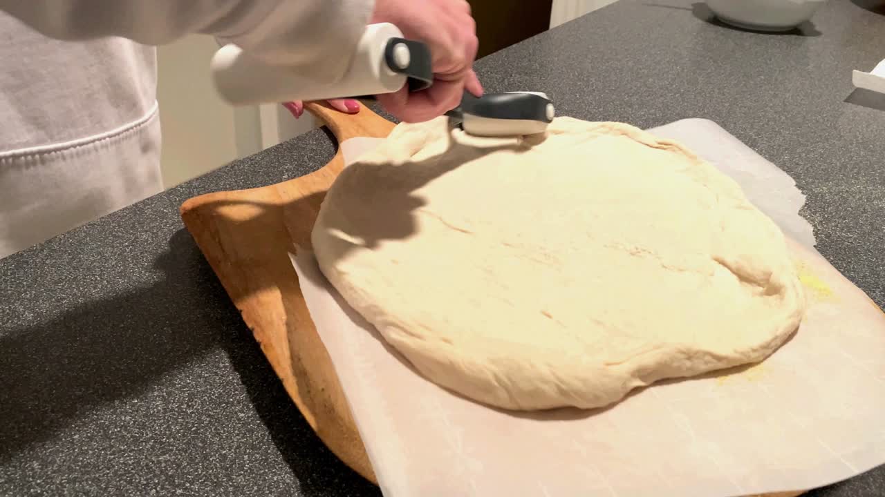 разворачивая свежее тесто для пиццы, чтобы сделать пирог