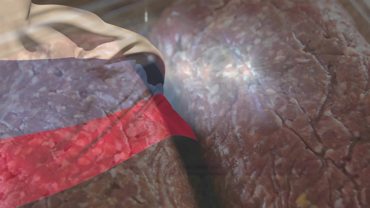 Carne macinata cruda che riempie un vassoio mentre un profilo traslucido si sposta e la telecamera zooma per rivelare la texture.