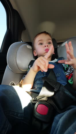 cute toddler boy eating something while riding in the car. kid sits comfortably at the back seat baby chair. low angle view.