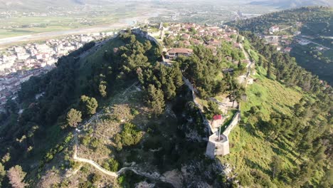 drone view in albania flying over berat medieval castle town on high ground with brick houses and stone wall surrounded by mountains