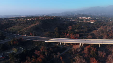 Rotación-Aérea-Sobre-Un-Puente-Al-Atardecer-En-Una-Ciudad-Suburbana