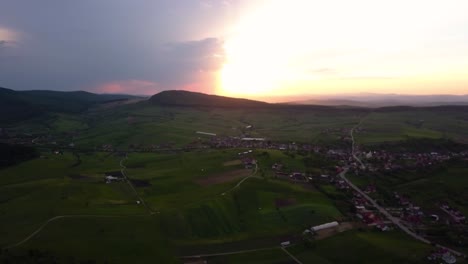 amplia toma aérea de una gran puesta de sol sobre amplios campos y prados verdes cerca de un inconveniente, transilvania, rumania