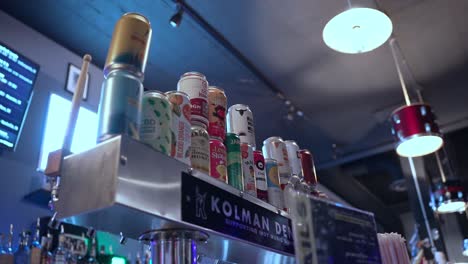 counter of a bar with colorful drinks in cans and behind lamps