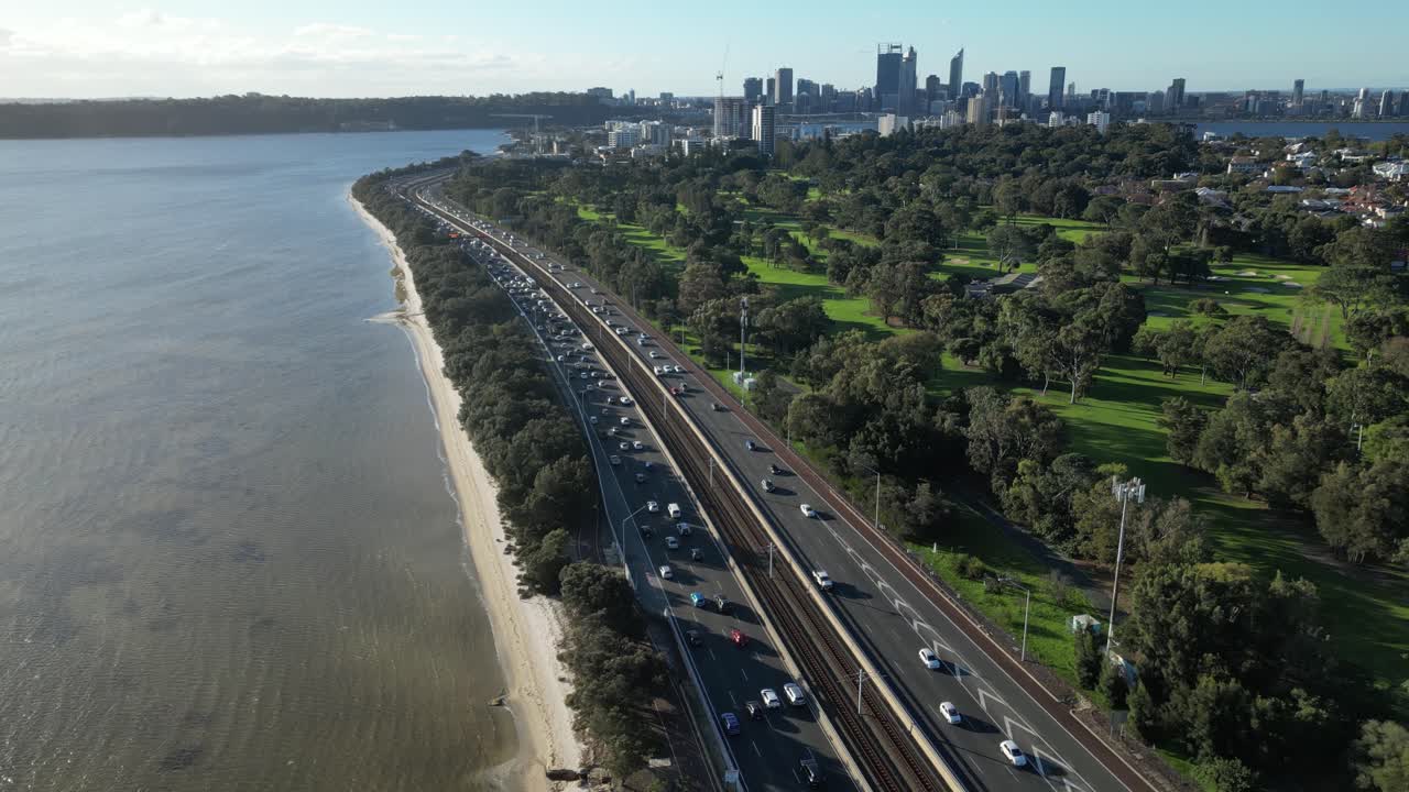 tráfico a lo largo de la autopista con club de golf y rascacielos de cbd en el fondo, ciudad de perth en australia