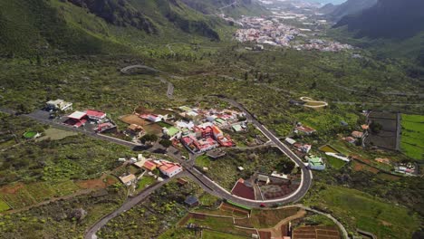 Tenerife-road-leading-through-small-town-towards-ocean-coastline,-aerial-view