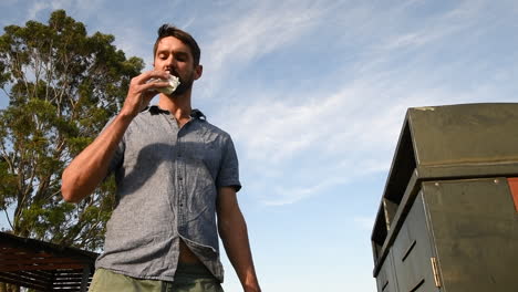 Man-eating-food-walks-to-bin-and-discards-half-eaten-food,-low-angle-outside