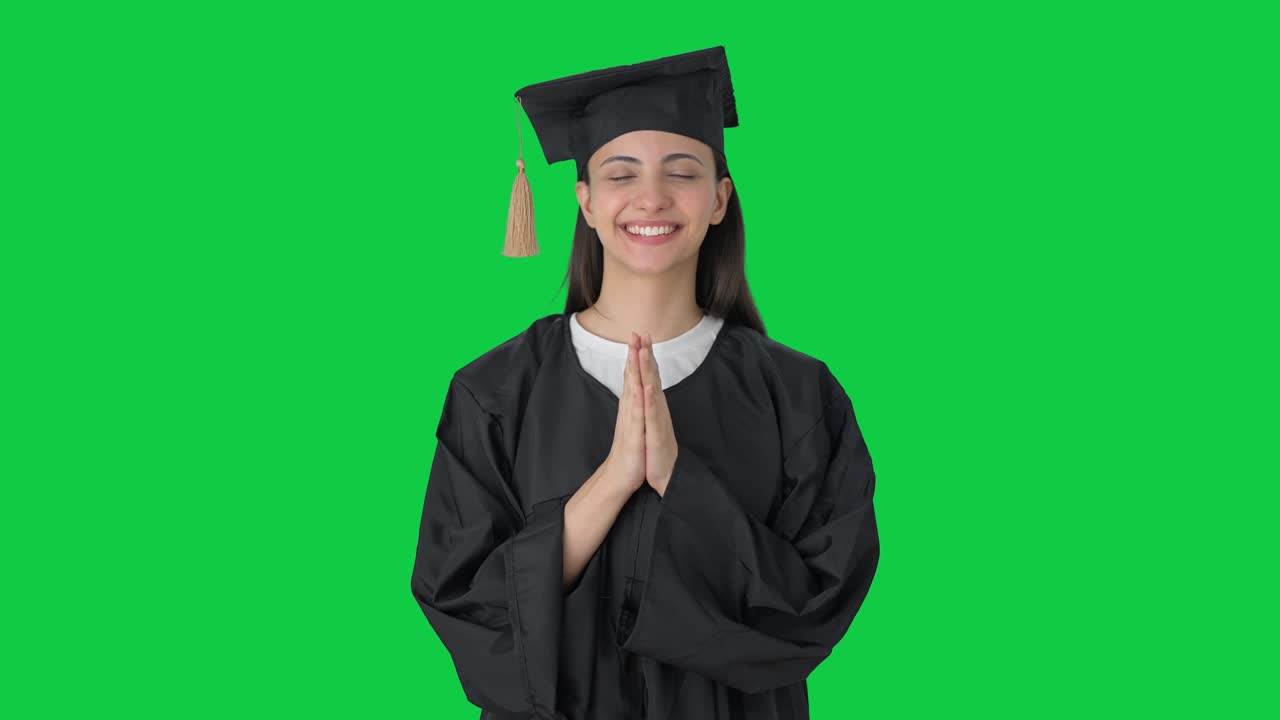 Felice ragazza indiana neolaureata che fa il Namaste su schermo verde.