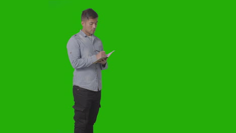 Three-Quarter-Length-Shot-Of-Male-University-Or-College-Student-Taking-Notes-In-Lecture-Or-Lesson-Against-Green-Screen-
