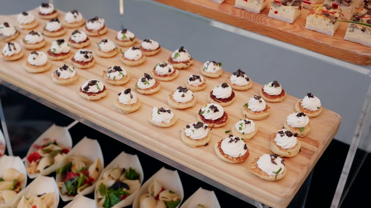 elegant display of bite sized blinis topped with cream and truffle served on a wooden tray