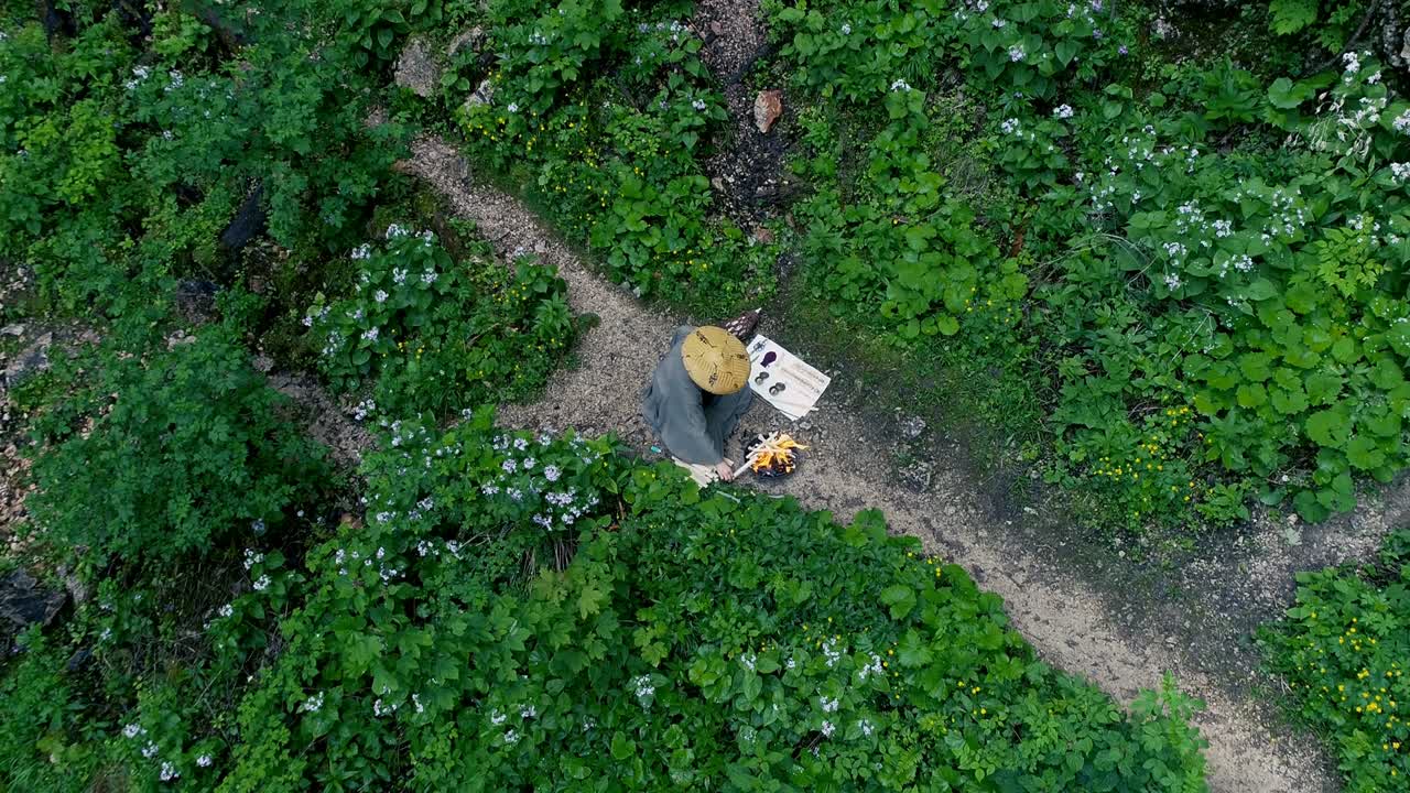 hombre con barba hace una ceremonia de fuego frente a una gran cascada