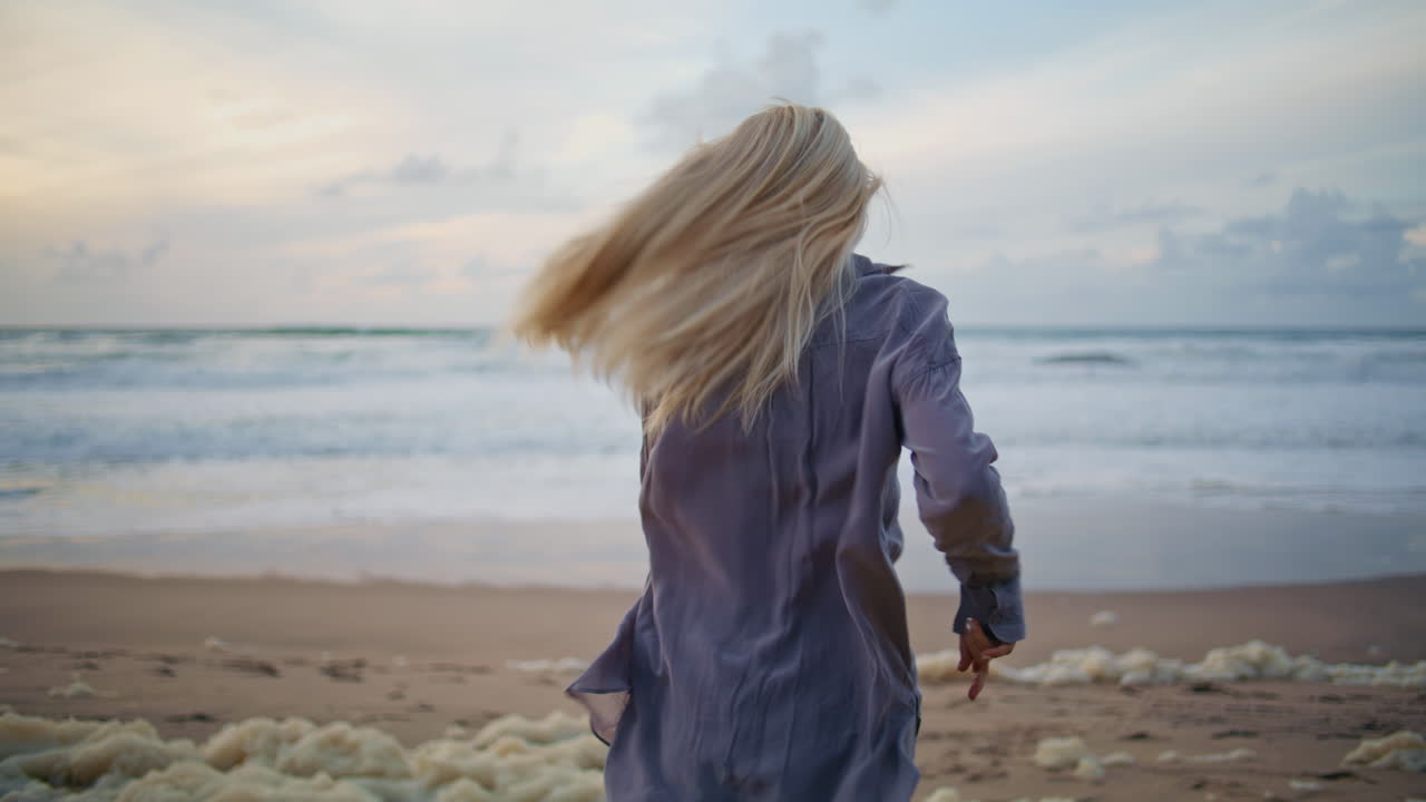 해가 지는 해변에서 달리는 소녀. 바다에서 저녁을 즐기는 무관심한 여성