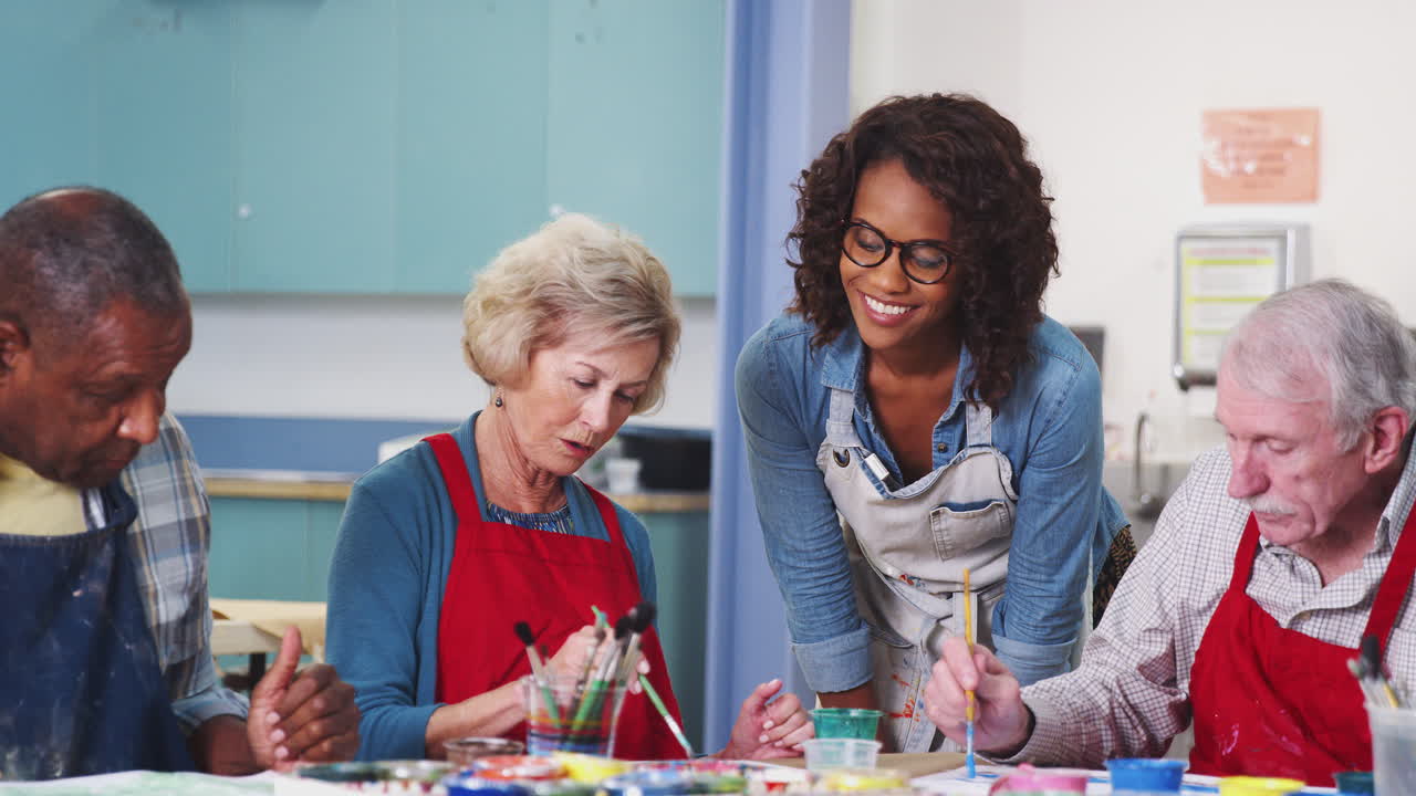 Group Of Retired Seniors Attending Art Class In Community Centre With Teacher