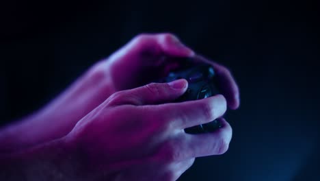 Playing-video-games-in-a-darkened-room-with-a-black-background-close-up-on-a-controller-buttons-playing-quickly-blue-lens-flare