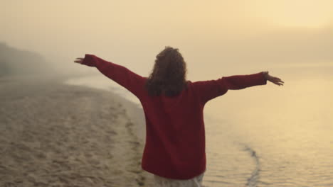 chica elegante corriendo en la playa de arena. mujer emocionada levantando las manos