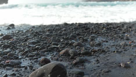 Vulkanstrand-Mit-Schwarzen-Kieselsteinen-Entlang-Des-Küstenstrandes,-Schwenk-In-Zeitlupe-Mit-Verschwommenen-Meereswellen-Von-Los-Gigantes,-Teneriffa