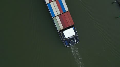 aerial top down view of stacked cargo containers being transported on river