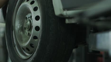 car mechanic removes a wheel, replaces the brake pads of the wheels of a raised car at a service station