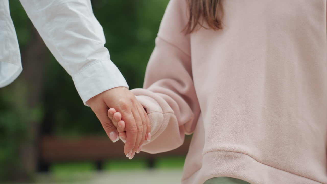 親と子が静かに散歩する。穏やかな公園で、母親が優しい仕草で娘をそっと慰める。静かで和やかな公園の環境の中、親子の調和のとれた散歩を楽しむ。