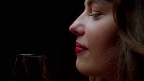 a beautiful woman is engaged in conversation while holding a glass of red wine - close up