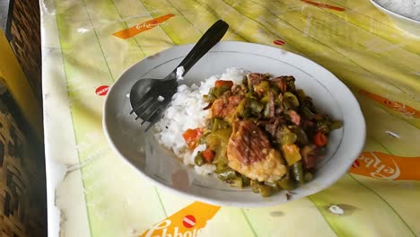 handheld pan of indonesian food green chili rice on plate on table