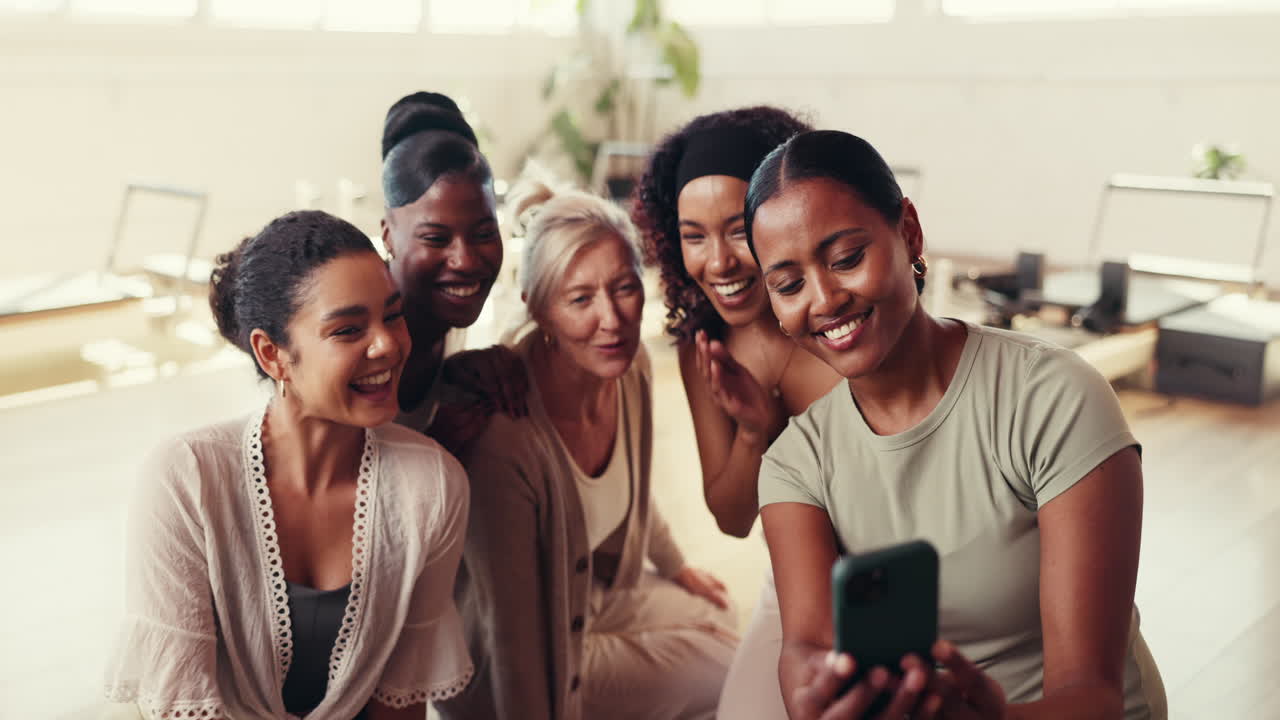 Gruppo di donne diverse che ridono e guardano un telefono