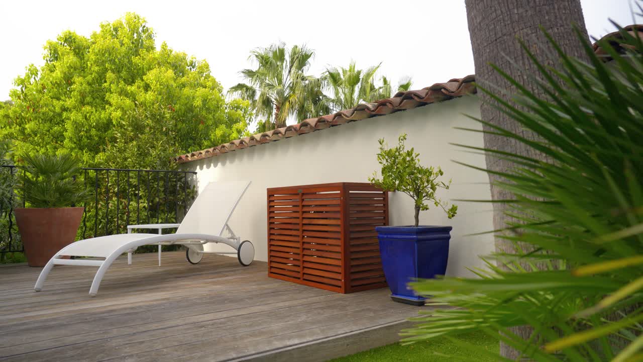 Modern patio with AC unit cover, lounger, and lush greenery in stylish setting