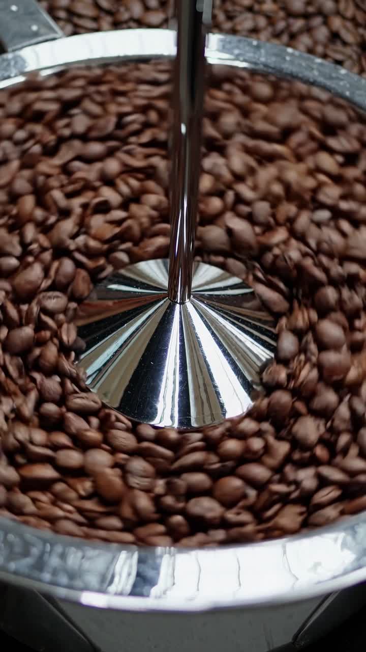 Close-up video of coffee beans swirling in a metal roaster, captured from a top-down angle