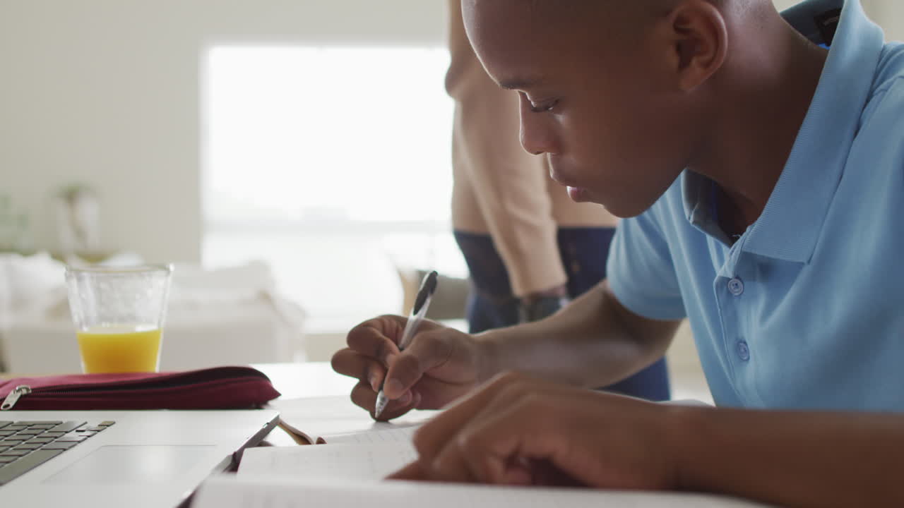 Video of focused african american boy having online lessons at home