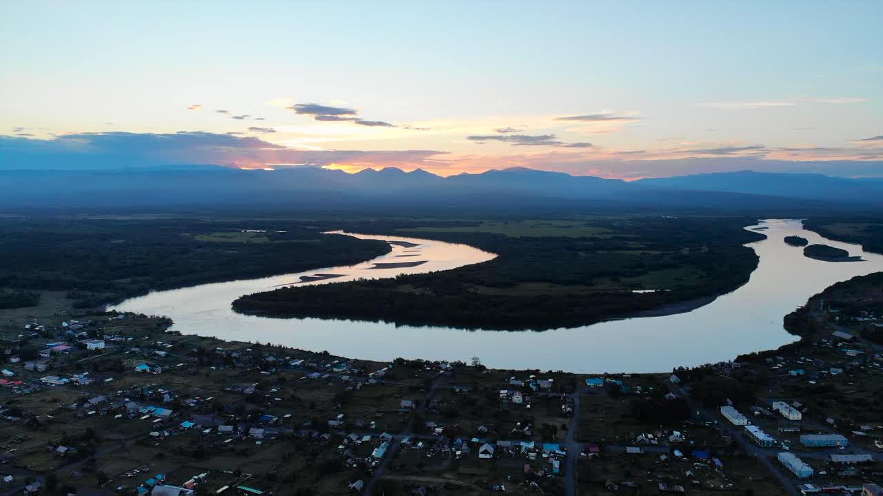 Aerial View of River, Mountains, and Village at Sunset