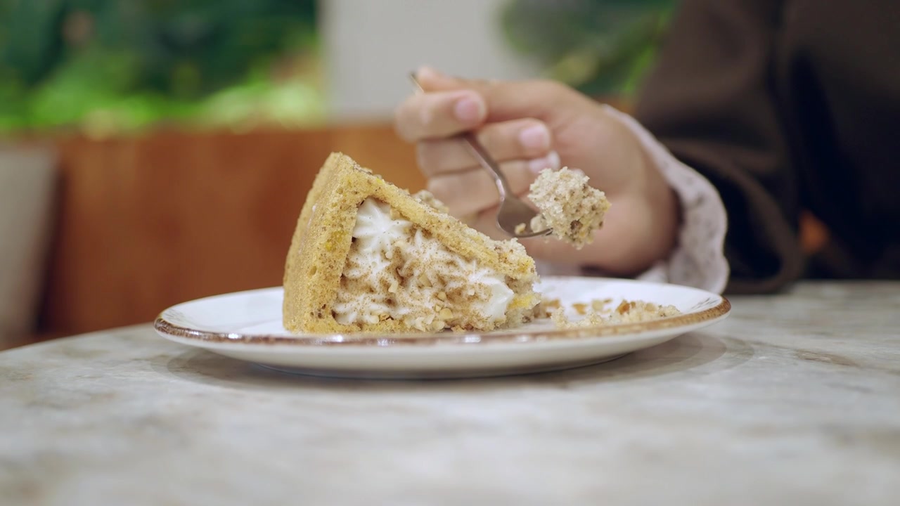 Person Eating a Slice of Creamy Cake in a Cafe