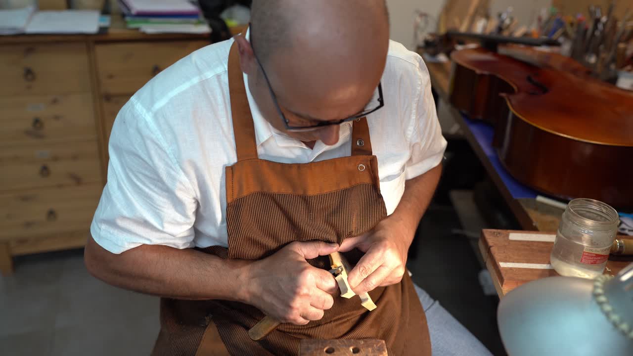 Luthier with violin bridge in workshop