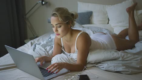 mujer en ropa interior escribiendo en la computadora portátil