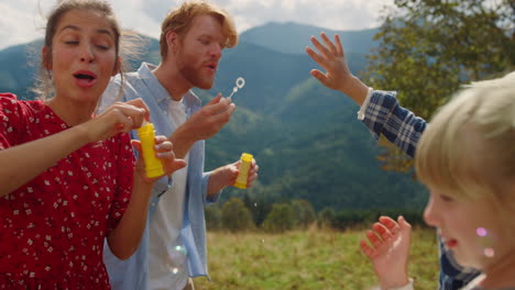 family enjoy blowing soap bubbles for children closeup. couple playing with kids