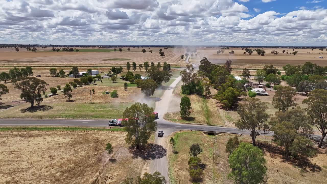 Large freight truck drives on dusty outback road in remote Australian farming landscape