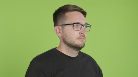 man in glasses removes protective kn95 face mask while looking right of camera on green screen chroma key