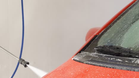 Pressure-hose-cleaning-red-car-in-car-wash