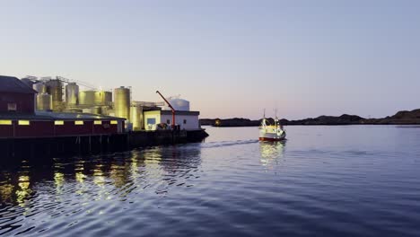 Fischerboot-Nähert-Sich-Während-Der-Goldenen-Stunde-Einem-Steg-Auf-Den-Lofoten,-Klarer-Himmel,-Ruhiges-Wasser