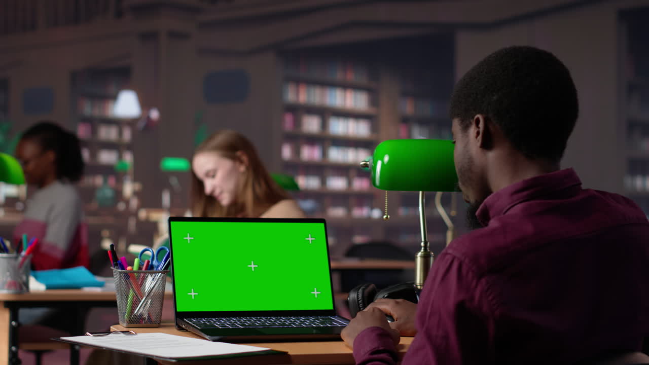 Vertical video young student working with a green screen in the university campus library