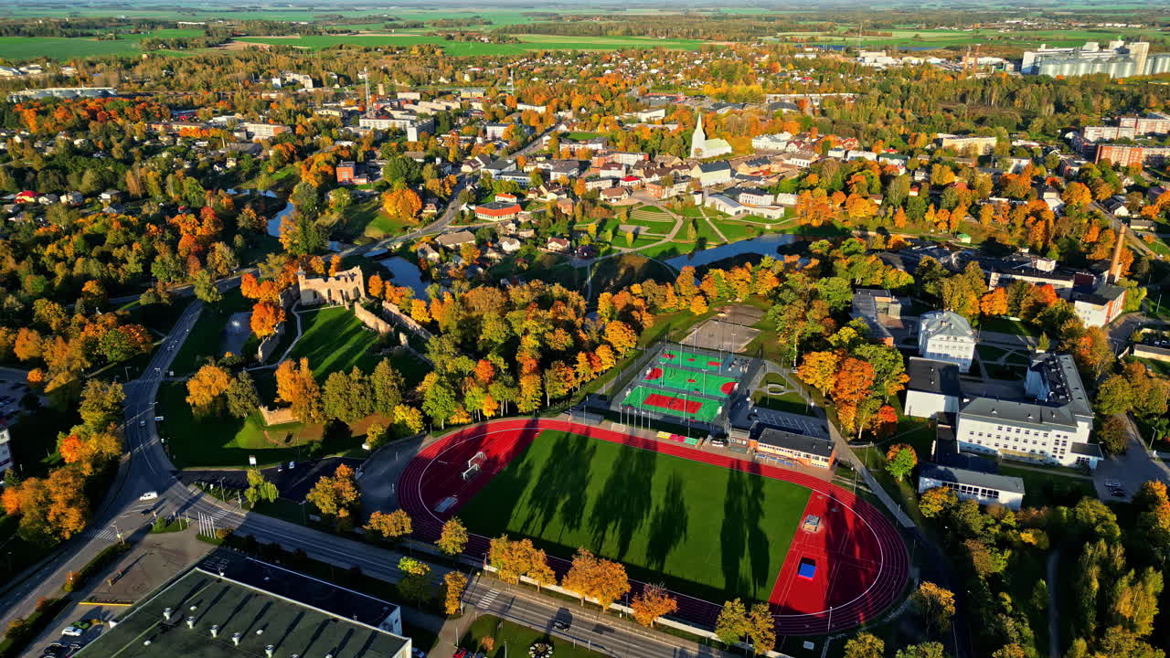 Aerial of the town of Dobele, Latvia in autumn, with an athletic field, houses, and trees