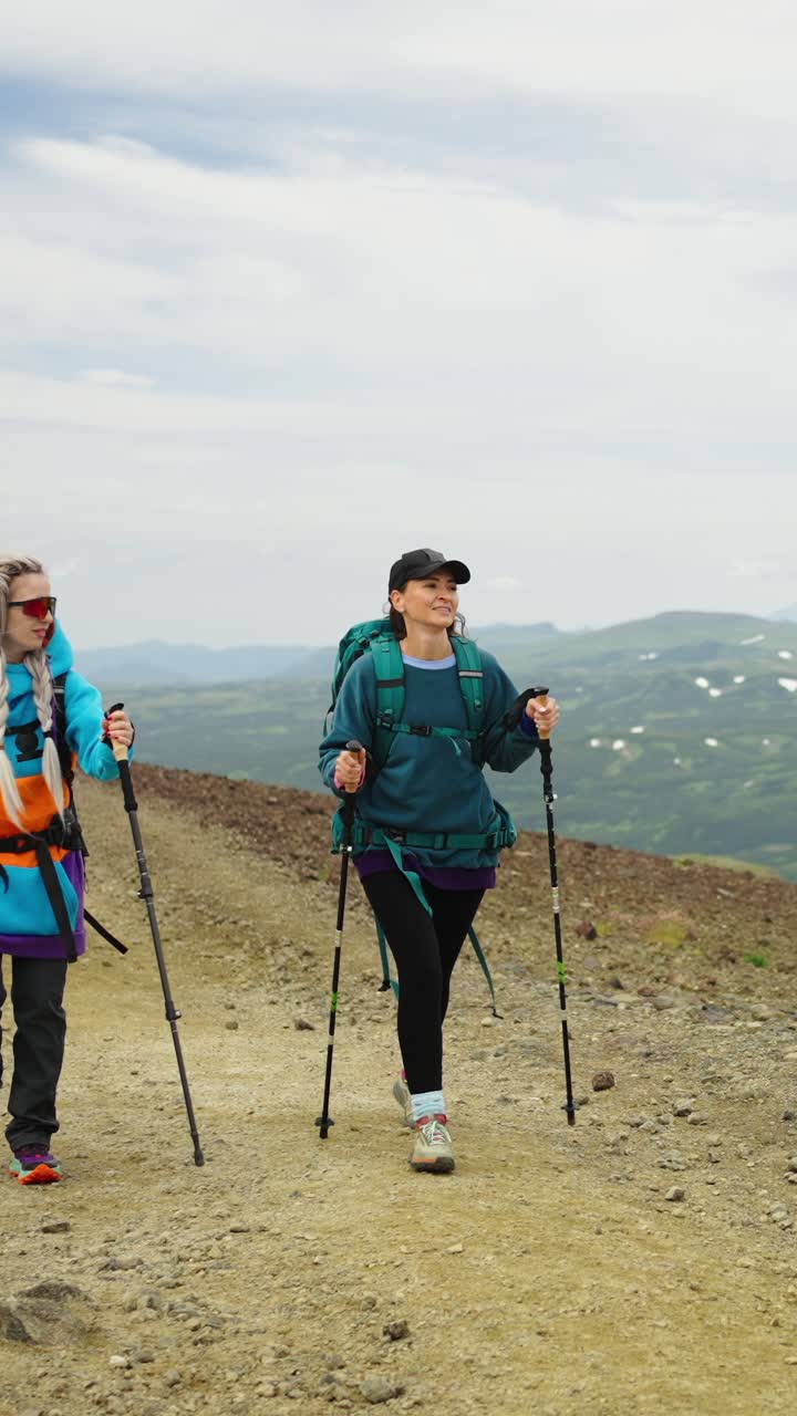 Due donne in escursione in salita su un sentiero di montagna con zaini