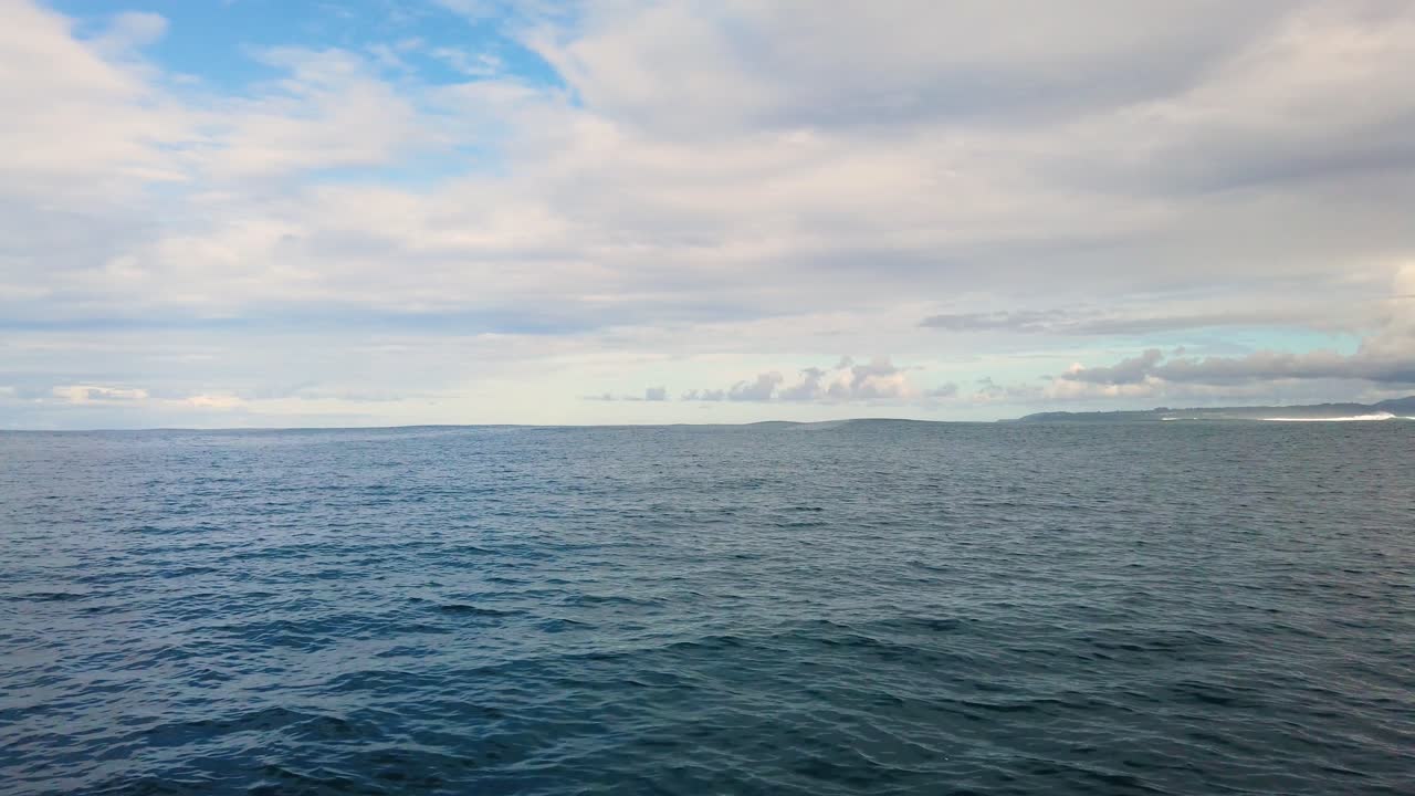 4K Hawaii Kauai: Bådtur på havet, der flyder fra højre mod venstre for at afsløre bølger og overskyet kystlinje i det fjerne.