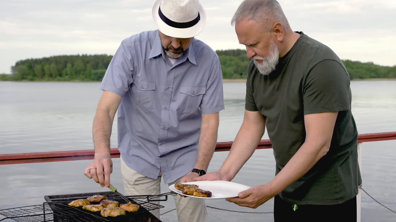 Two senior men cooking. It's a barbecue.